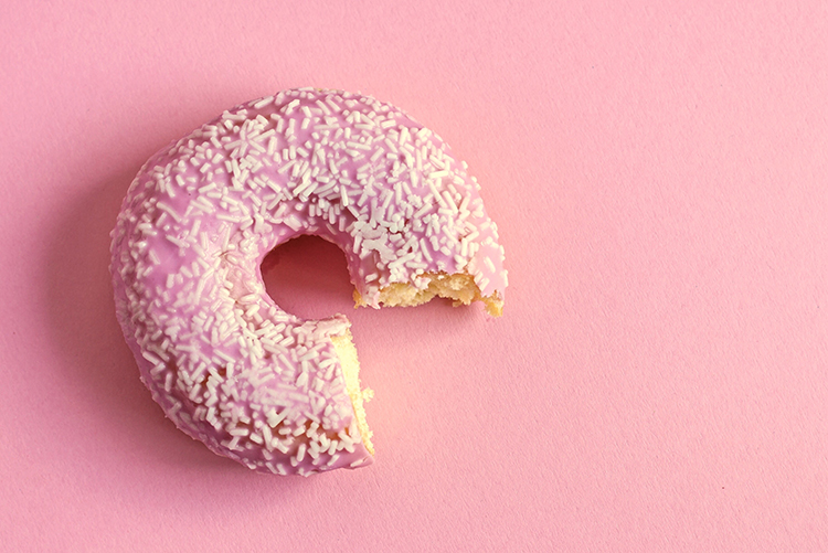 Close-Up Of Eaten Donut Over Pink Background