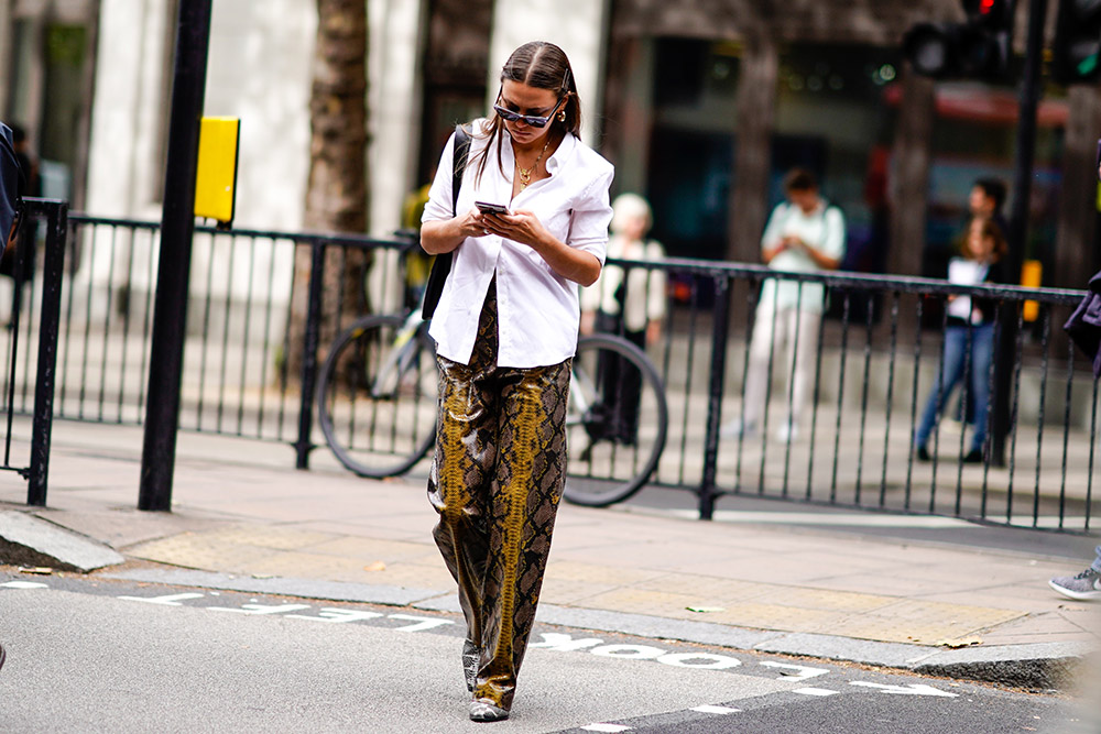 A guest wears a white shirt, snake print leather flared pants, during London Fashion Week September 2018 on September 18, 2018 in London, England. (Photo by Edward Berthelot/Getty Images)