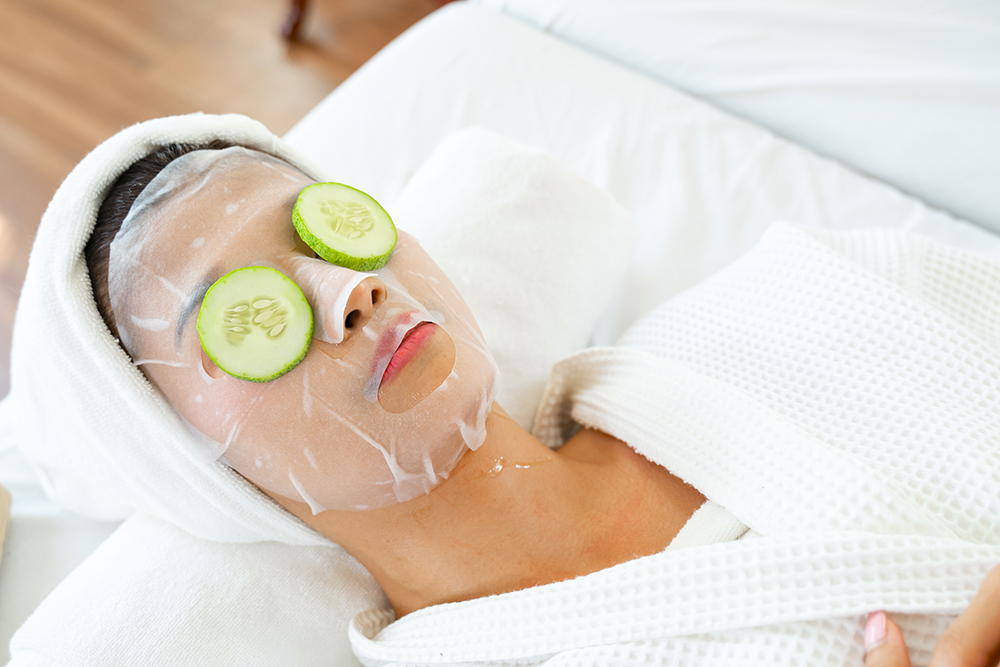 Woman at home spa with sheet mask and cucumbers on her closed eyes