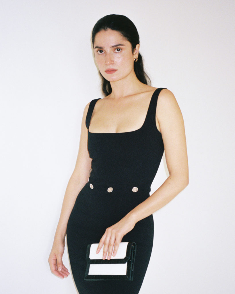 model wearing black Paris Georgia dress, holding a mini bag by Paris Georgia x By Far